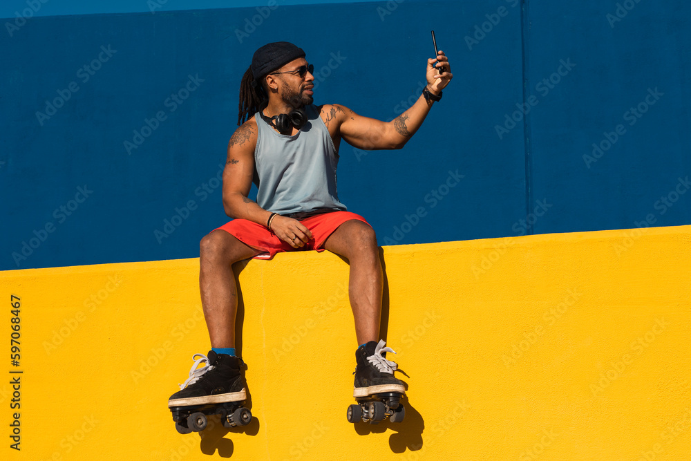 Black man taking selfie photo outside. Urban man posing with roller skates. Black man taking selfie photo outside. Urban man posing with roller skates.
