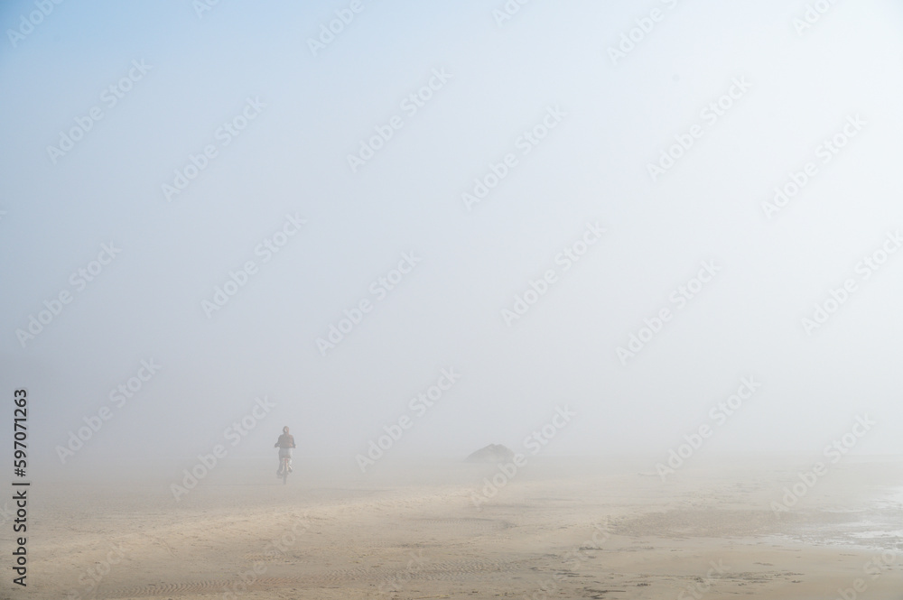 Fog on Baltic sea coastline at spring. Moody weather, mist. Cyclist riding in mist