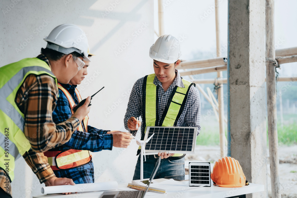 .Architect team working with blueprints for sketching a construction project, green energy and solar panel concept. .Architect team working with blueprints for sketching a construction project, green energy and solar panel concept.