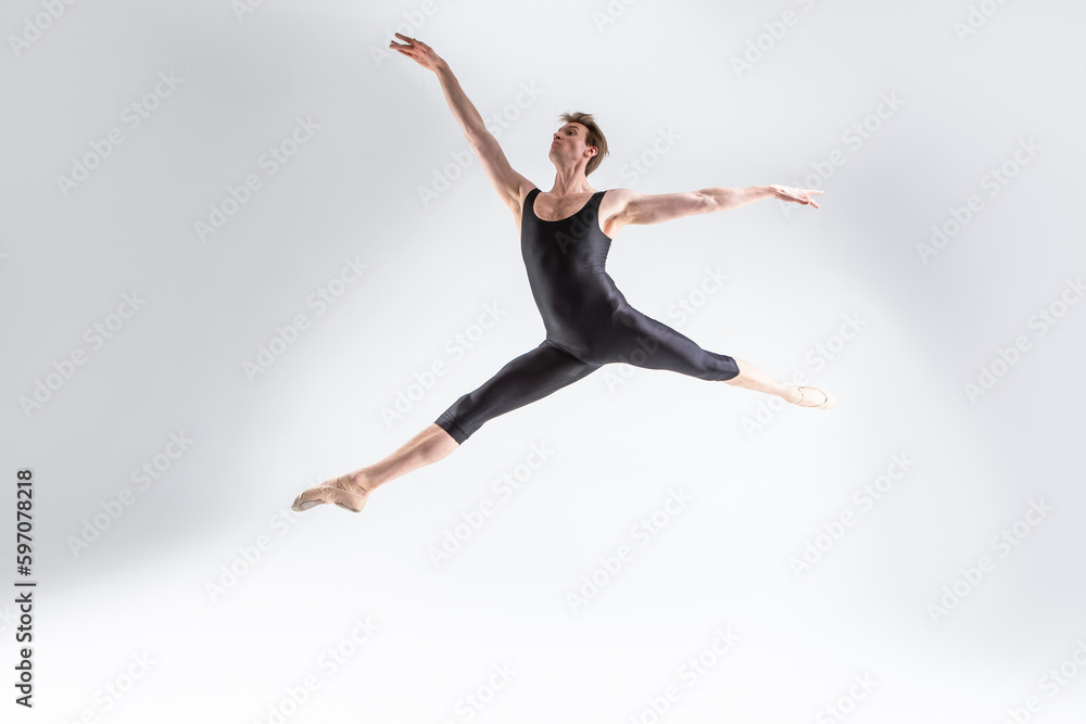 Art Ballet of Young Caucasian Athletic Man in Black Suit Dancing in Studio Over White Background With Lifted Hands. Art Ballet of Young Caucasian Athletic Man in Black Suit Dancing in Studio Over White Background With Lifted Hands.