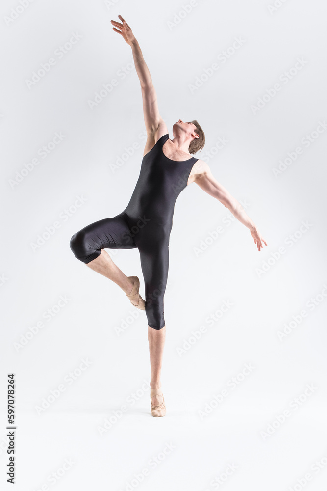 Male Ballet Dancer Young Caucasian Athletic Man in Black Suit Posing Flying Dancing in Studio On White With Lifted Hands.