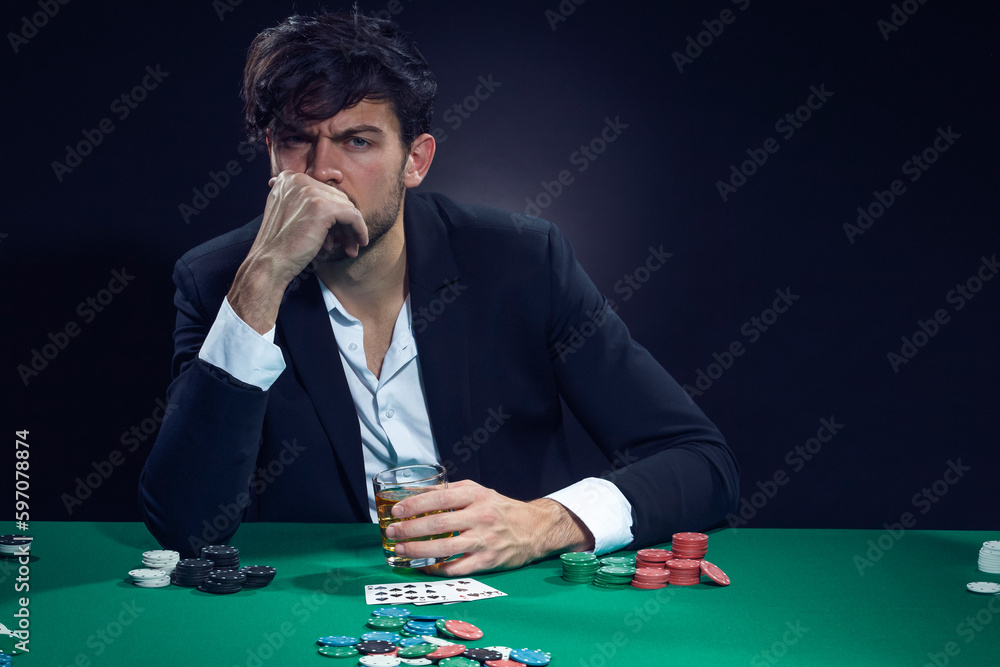 Gambling Concepts. Thoughful Handsome Caucasian Brunet Cards Player At Pocker Table With Chips and Cards While Playing and Drinking Alcohol. Gambling Concepts. Thoughful Handsome Caucasian Brunet Cards Player At Pocker Table With Chips and Cards While Playing and Drinking Alcohol.