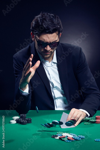 Gambling Concepts. One Emotional Handsome Caucasian Brunet Cards Player At Pocker Table With Chips Flying and Cards While Playing and Drinking Alcohol