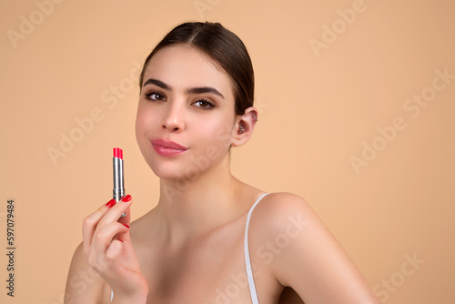 Photo of shirtless woman posing with lipstick, isolated studio background. Beautiful woman holding with naked shoulder hold lipstick. Sexy girl using lipstick.