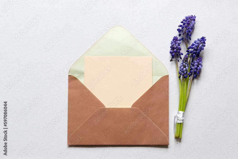 Flat lay composition with muscari flowers and envelope mockup with blank greeting card on light background. Minimal floral frame. Top view. Happy mother's day, women's day, birthday or wedding. Flat lay composition with muscari flowers and envelope mockup with blank greeting card on light background. Minimal floral frame. Top view. Happy mother's day, women's day, birthday or wedding.