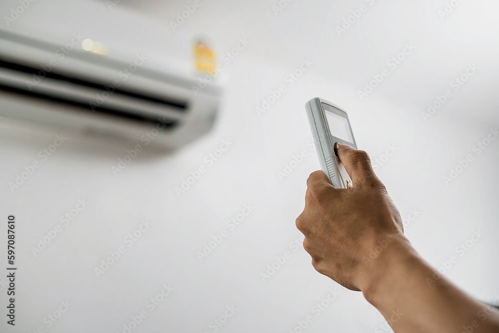 Fototapeta premium Air conditioner maintenance technician hand pressing remote control air conditioner background