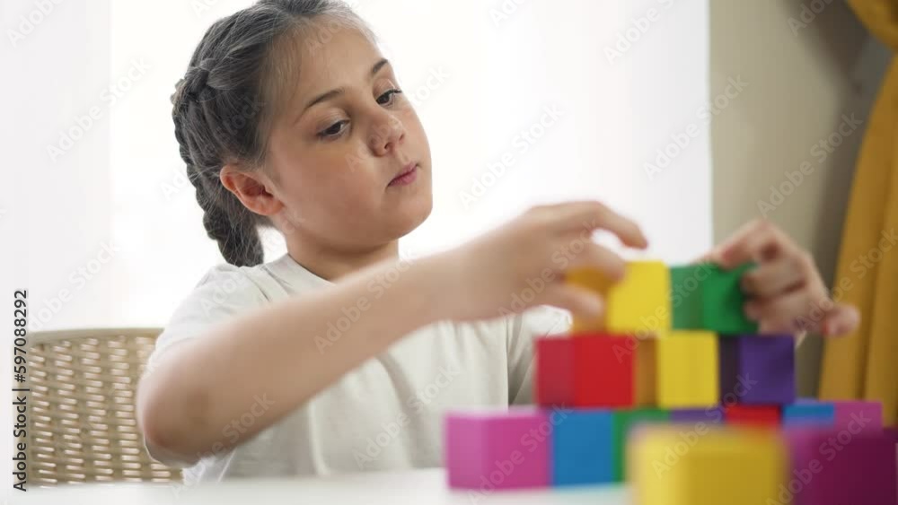 Adorable children play in kindergarten and at home. Colored cubes and toys on table. Child collects toys in kindergarten. Child home game. Concept of family happy.Kid with colored cubes plays at table Adorable children play in kindergarten and at home. Colored cubes and toys on table. Child collects toys in kindergarten. Child home game. Concept of family happy.Kid with colored cubes plays at table