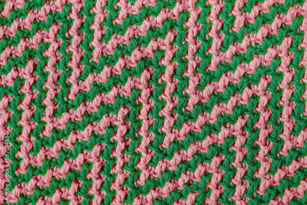 Knitted texture with chevron pattern. Texture of mosaic fabric with pink green geometric ethnic pattern. Crochet mosaic pattern.