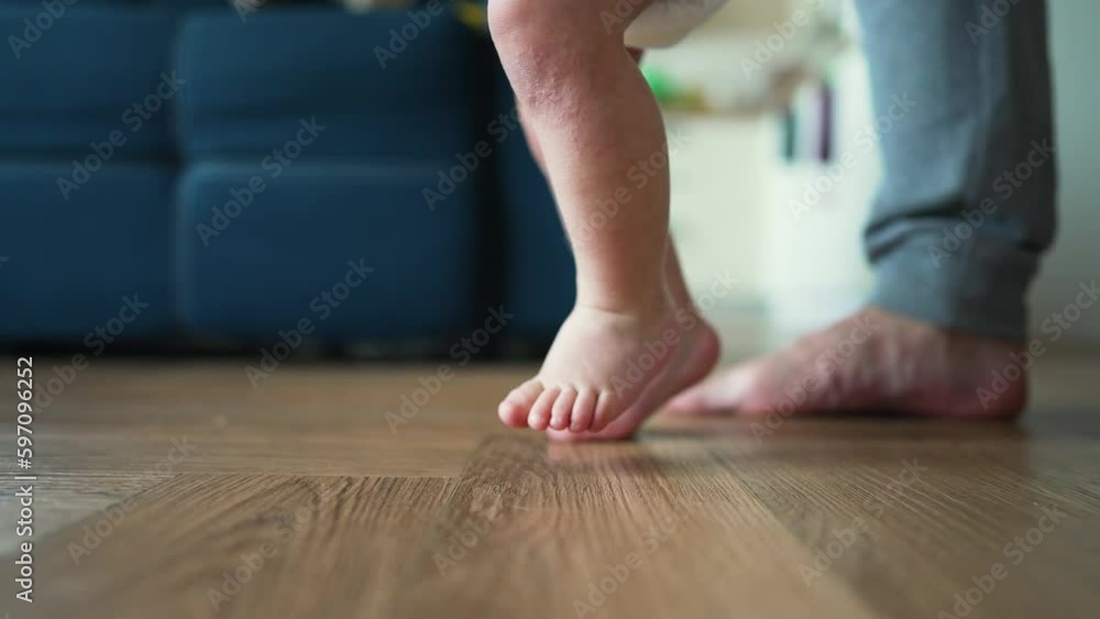 Father helps his son take his first steps on parquet floor. first ...