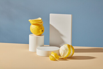 Minimal background with blank space to placed your design or packaging mockups. White empty podium, cylinders geometric and fresh lemons on blue background. Advertising product of lemon extract.