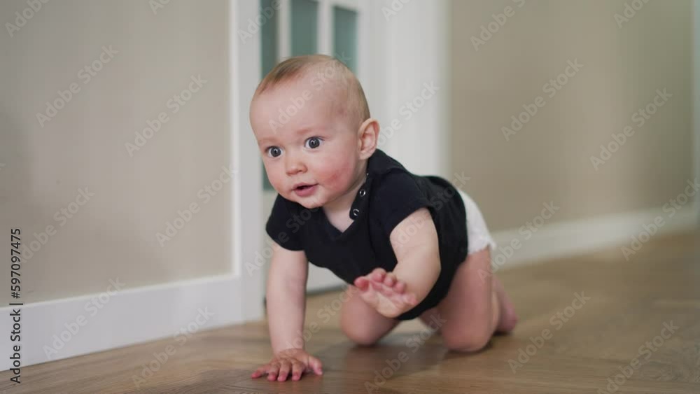 Happy and curious child explores his house by crawling on parquet floor. Happiness and satisfaction on face of child. Baby crawls across floor towards his parent. Baby learns to move on floor at home Happy and curious child explores his house by crawling on parquet floor. Happiness and satisfaction on face of child. Baby crawls across floor towards his parent. Baby learns to move on floor at home