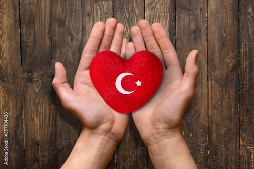 Human hands hold red heart with Turkey flag
