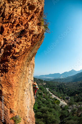 The girl climbs the rock. Climber trains on natural terrain. Extreme sport. Lessons on the street. A woman overcomes a difficult climbing route in Turkey.