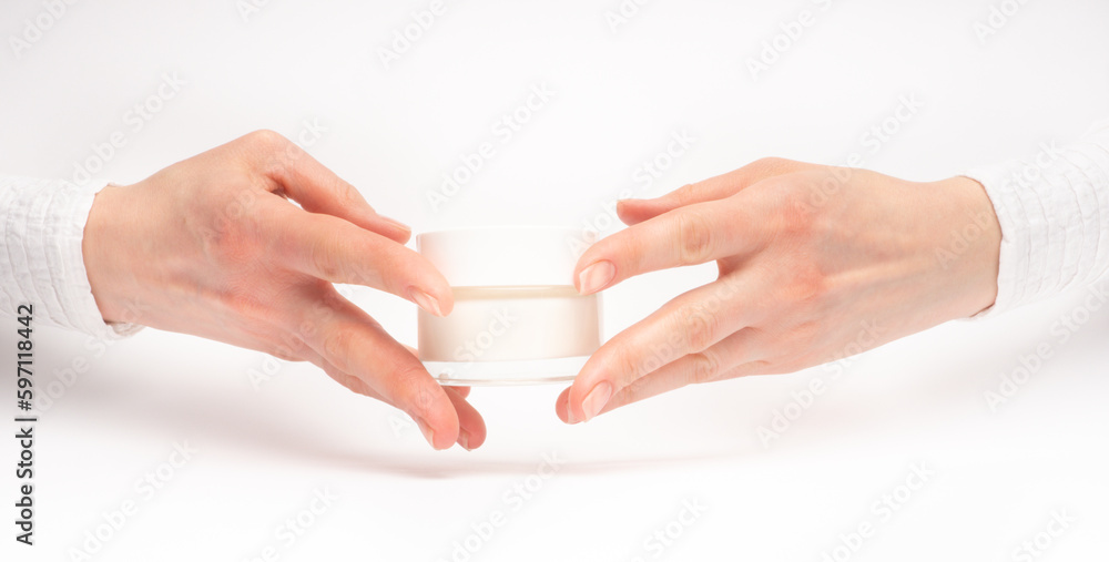 Mock-up of beautiful woman's hand holds round jar or container of cosmetic product cream or lotion on white isolated background. Concept of beauty, spa industry, skin care. Close-up, copy space