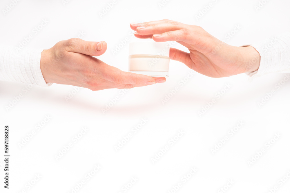 Mock-up of beautiful woman's hand holds round jar or container of cosmetic product cream or lotion on white isolated background. Concept of beauty, spa industry, skin care. Close-up, copy space
