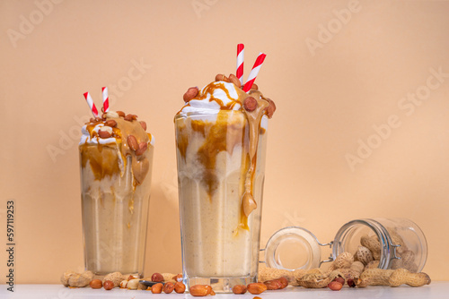 Peanut butter smoothie, milk shake with a lot of peanuts and caramel sauce, beige background copy space
