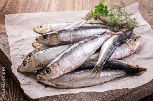 Fresh Portuguese raw anchovies with onion rings and herbs offered as close-up on stone tray