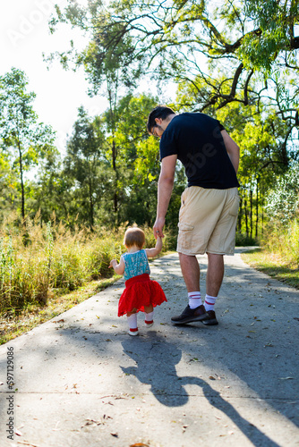 Little girl walking down footpath with dad photo