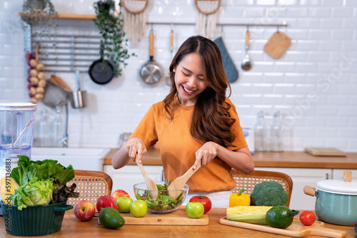 Beautiful young woman happy portrait cooking fresh organic clean food fruit at home modern kitchen