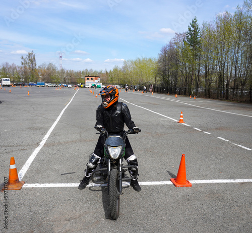 A young woman is learning to ride a motorbike in a motorcycle school. She is taught by a teacher.