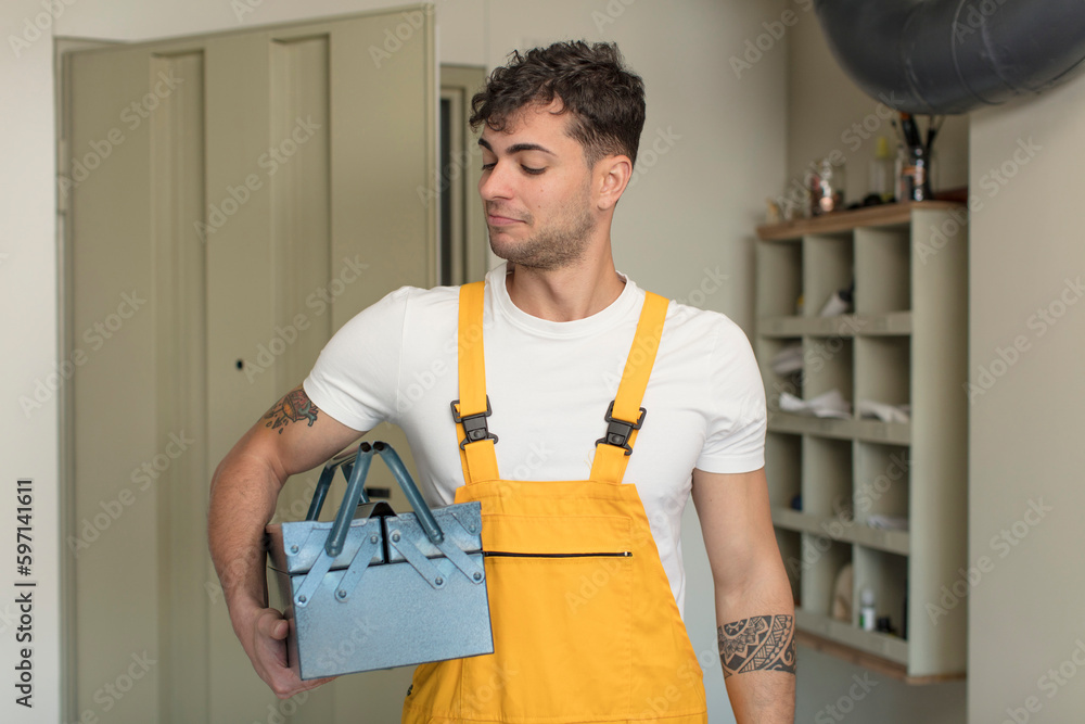 young handsome man smiling and looking with a happy confident expression. handyman concept young handsome man smiling and looking with a happy confident expression. handyman concept