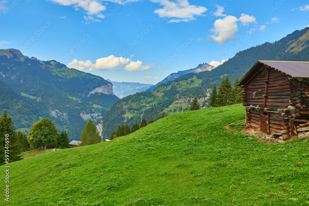 Mountain view with wooden barn on the eadow near Wengen village in Switzerland.