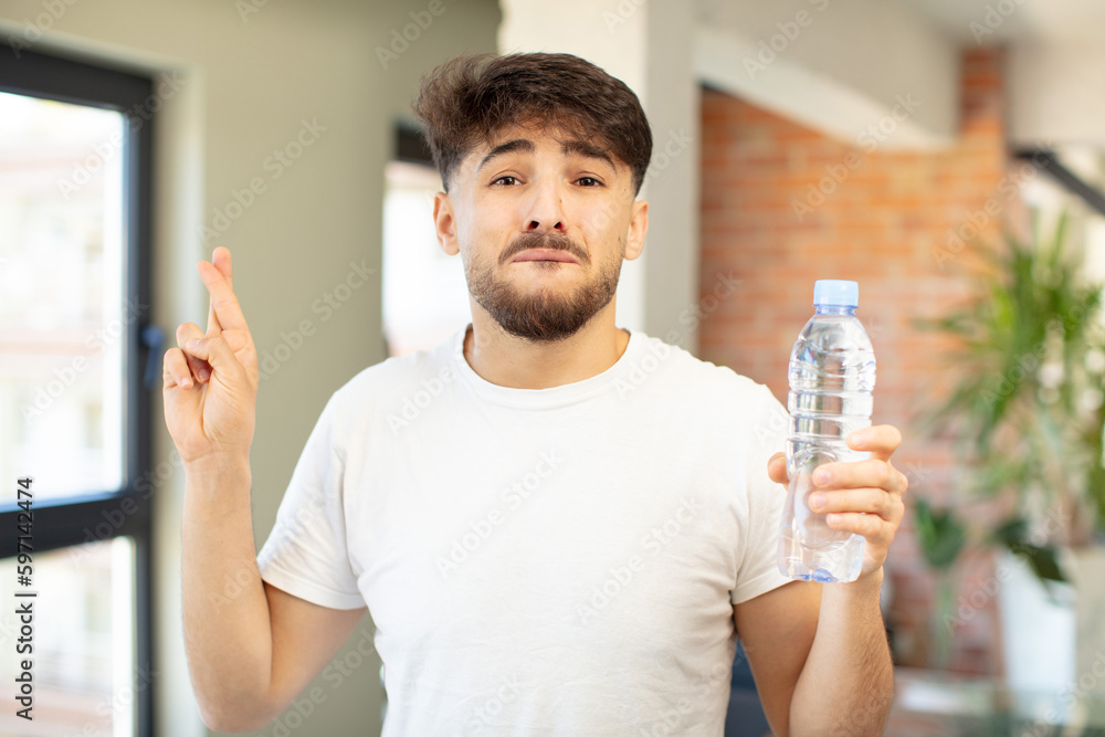 young handsome man crossing fingers and hoping for good luck. water bottle concept young handsome man crossing fingers and hoping for good luck. water bottle concept