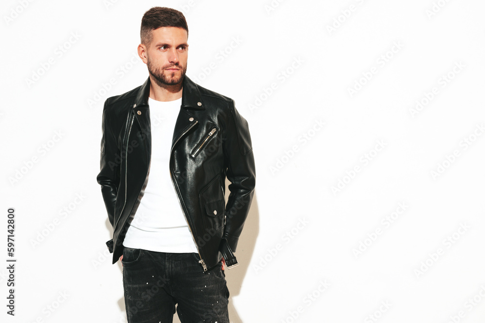 Portrait of handsome confident model. Sexy stylish man dressed in biker leather jacket and black jeans. Fashion hipster male isolated on white in studio Portrait of handsome confident model. Sexy stylish man dressed in biker leather jacket and black jeans. Fashion hipster male isolated on white in studio