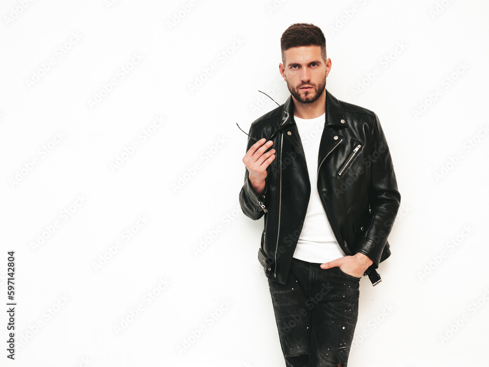 Portrait of handsome confident model. Sexy stylish man dressed in biker leather jacket and black jeans. Fashion hipster male isolated on white in studio Portrait of handsome confident model. Sexy stylish man dressed in biker leather jacket and black jeans. Fashion hipster male isolated on white in studio