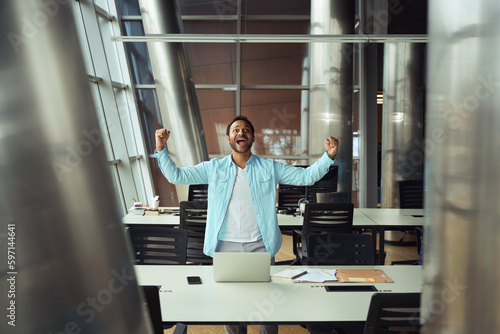 Happy male rejoices at job in the office