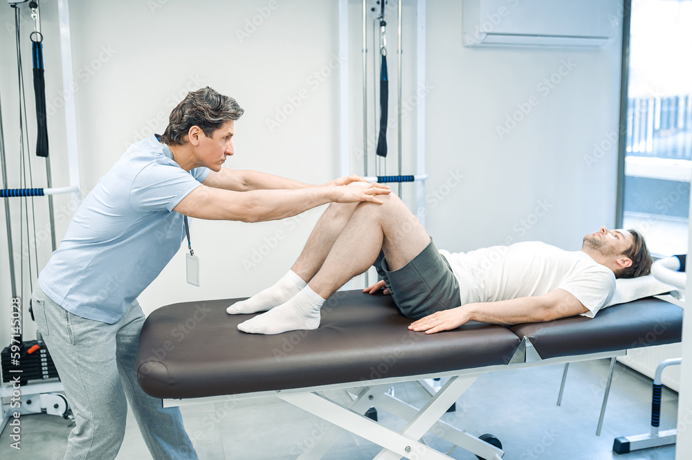 Male physical therapist working with patients legs