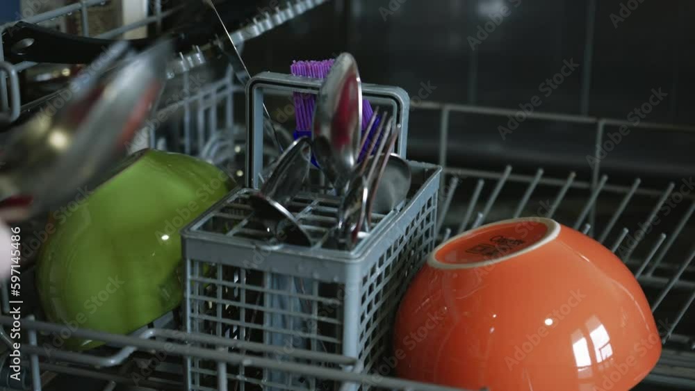 Loading dirty plates, crockery and glass into the dishwasher. Puts