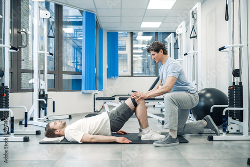 Experienced instructor assisting a man in a rehabilitation workout