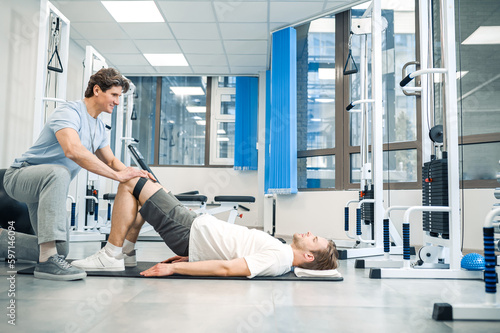 Experienced instructor assisting a man in a rehabilitation workout