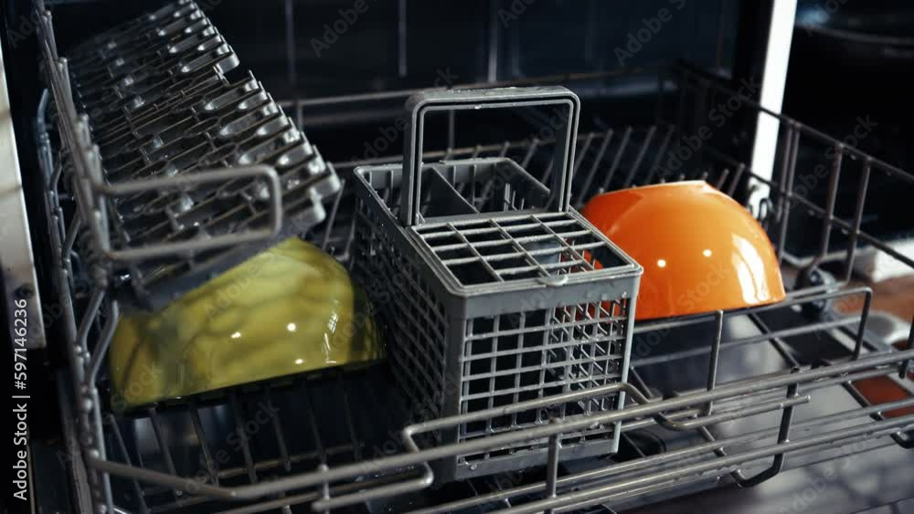 Loading dirty plates, crockery and glass into the dishwasher. Puts