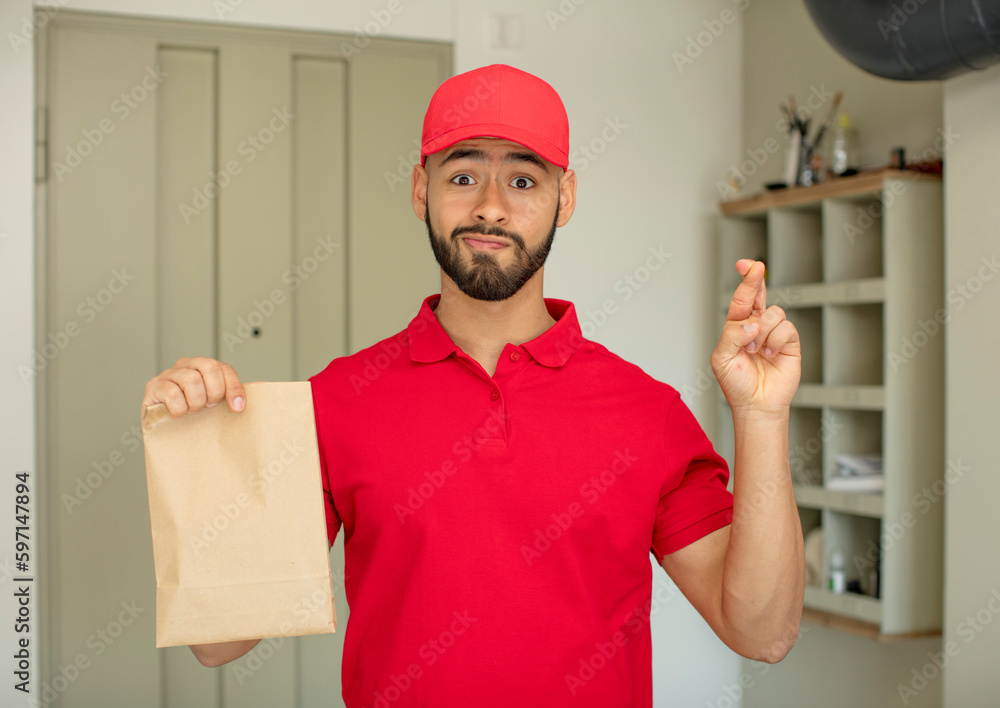 young adult man crossing fingers and hoping for good luck. deliveryman concept young adult man crossing fingers and hoping for good luck. deliveryman concept