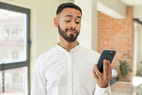young  adult man smiling and looking with a happy confident expression. smartphone concept