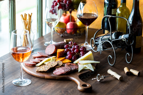 A charcuterie board of gourmet meats and cheese with red  white and rose wine.