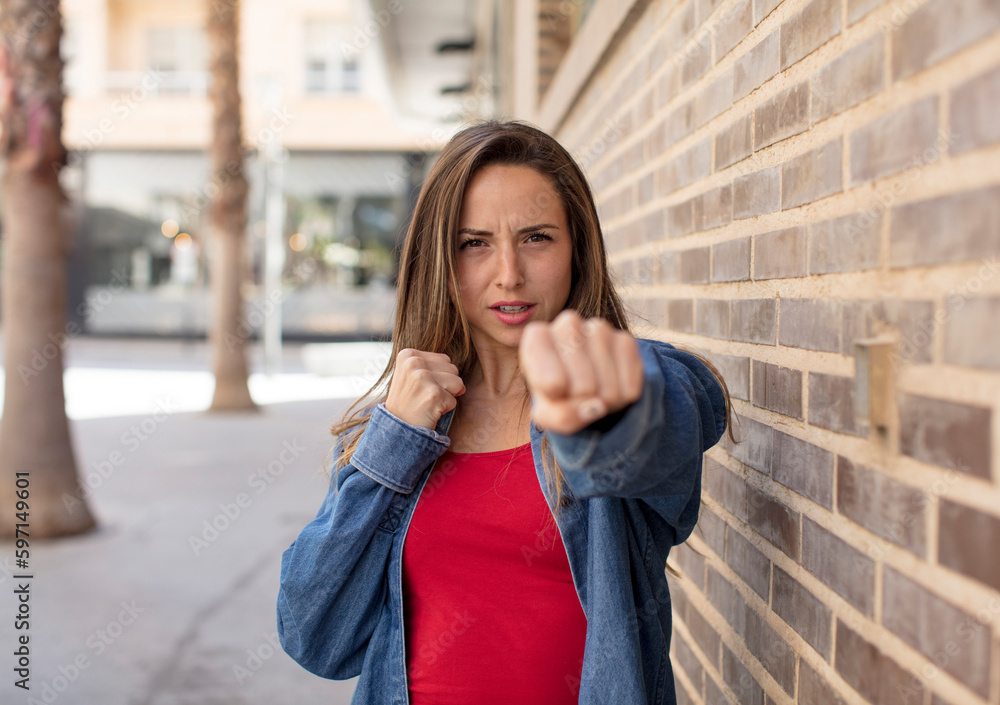 pretty woman looking confident, angry, strong and aggressive, with fists ready to fight in boxing position