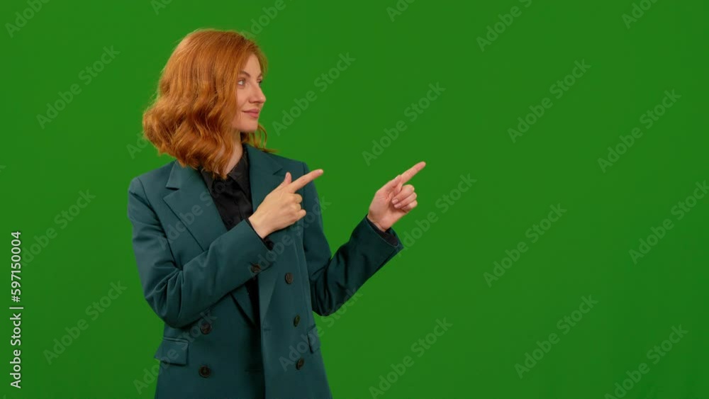 Woman smiling and looking at camera pointing her fingers at left top side over green screen background. Female showing something important on screen.
