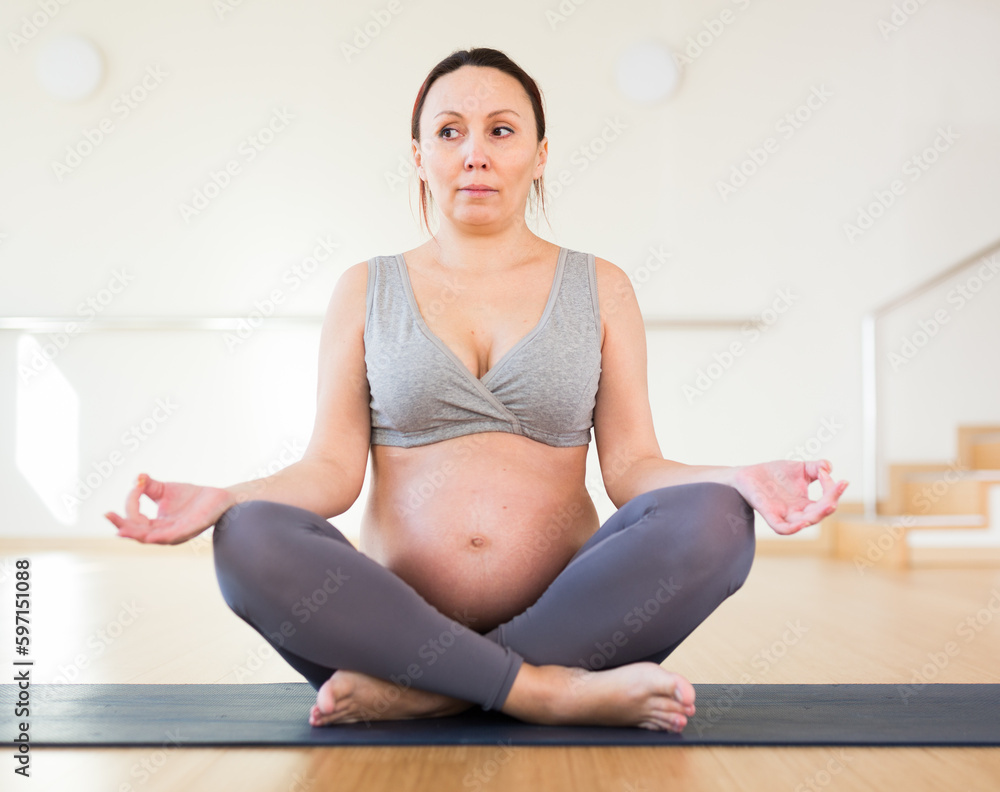Pregnant woman is engaged in yoga. Easy Pose or Sukhasana Pregnant woman is engaged in yoga. Easy Pose or Sukhasana