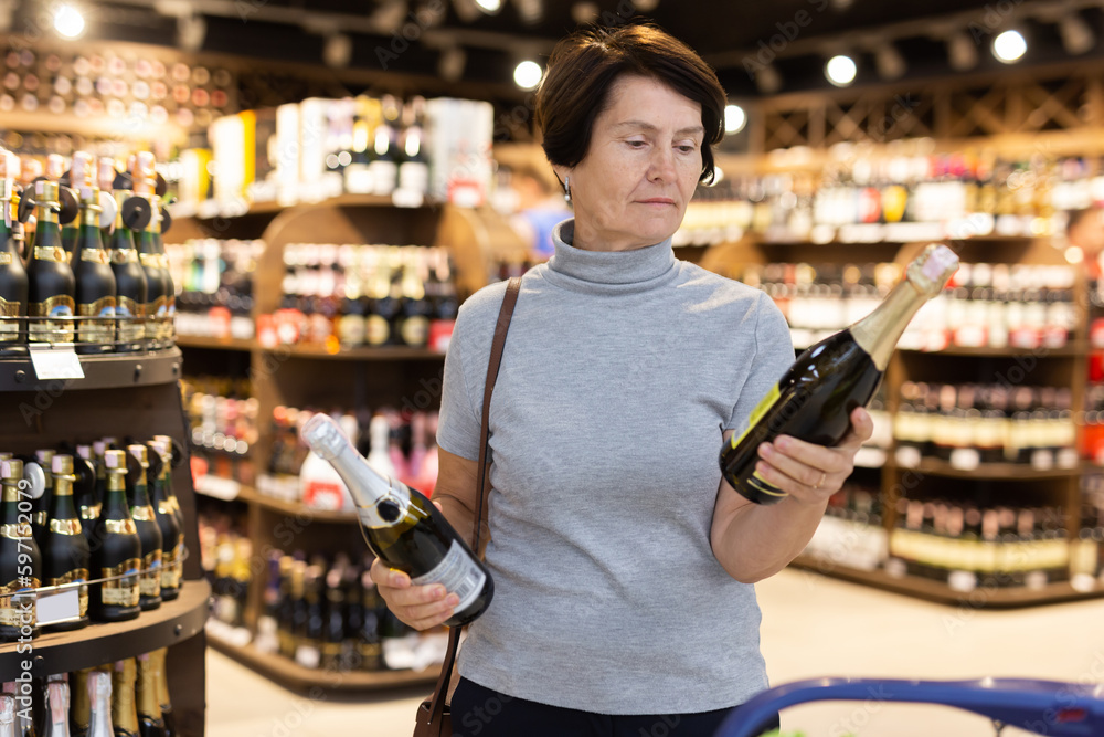 Elderly woman choose bottle of champagne Elderly woman choose bottle of champagne