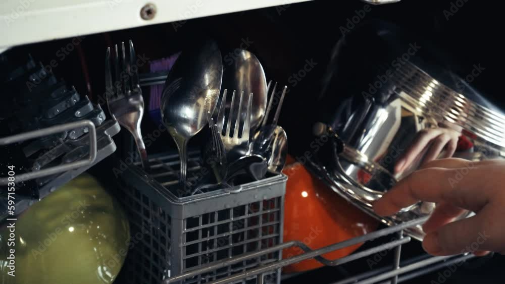 Loading dirty plates, crockery and glass into the dishwasher. Puts