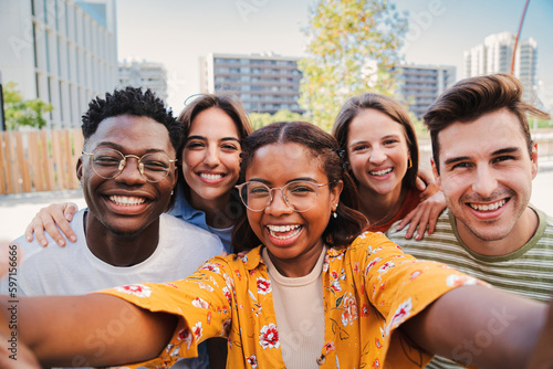 Group of multiracial young student people taking a selfie together looking at camera at the university campus. Close up portrait of happy african american teenager woman laughing with cheerful friends