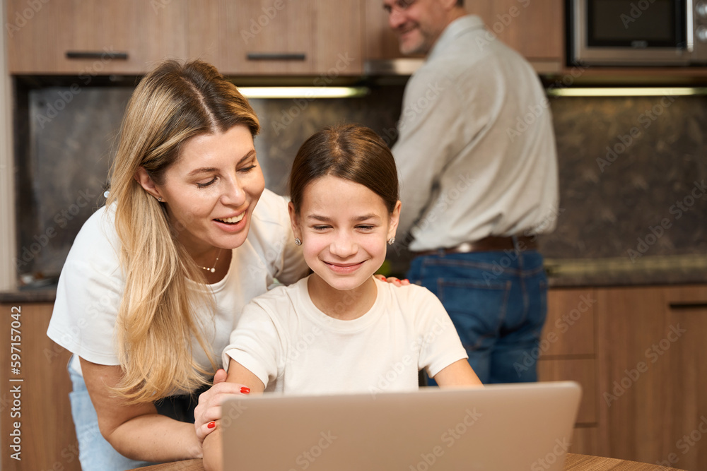 Cropped photo of happy mother and daugter with laptop in the kitchen Cropped photo of happy mother and daugter with laptop in the kitchen