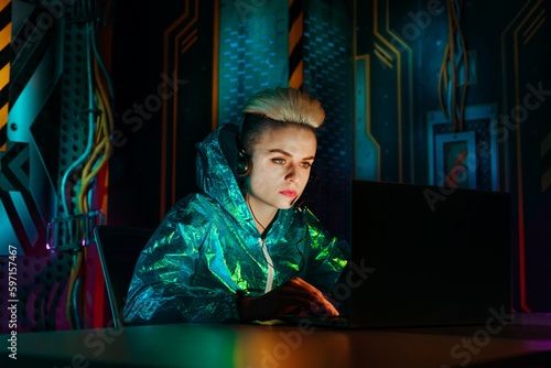 Gamer wearing headset playing video games on laptop at desk photo