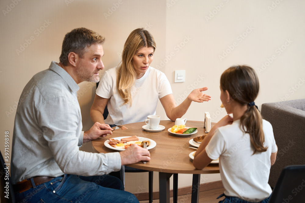 Family mother, father and dauter having breakfast in kitchen in hotel room Family mother, father and dauter having breakfast in kitchen in hotel room