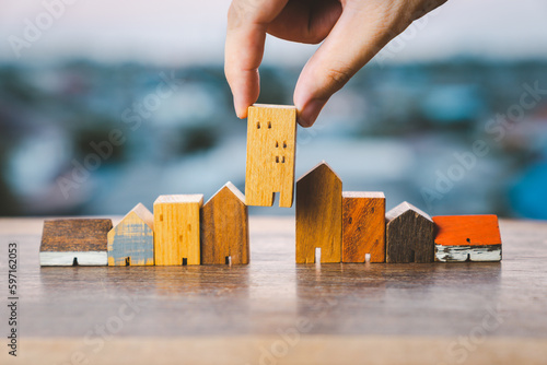 Bilde på lerret Hand choosing mini wood house model from model on wood table, selective focus, Planning to buy property