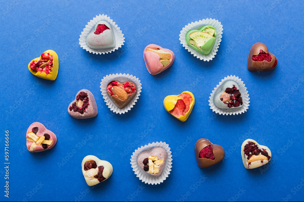 chocolate sweets in the form of a heart with fruits and nuts on a colored background. top view with space for text, holiday concept chocolate sweets in the form of a heart with fruits and nuts on a colored background. top view with space for text, holiday concept