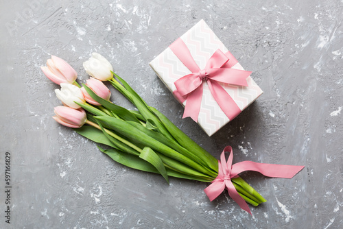 Pink tulips flowers and gift or present box on colored table background. Mothers Day  Birthday  Womens Day  celebration concept. Space for text top view